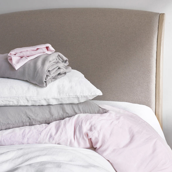 Pile of Freshly Cleaned Linen Bed Sheets and Pillowcases in White, Pink and Grey | Scooms