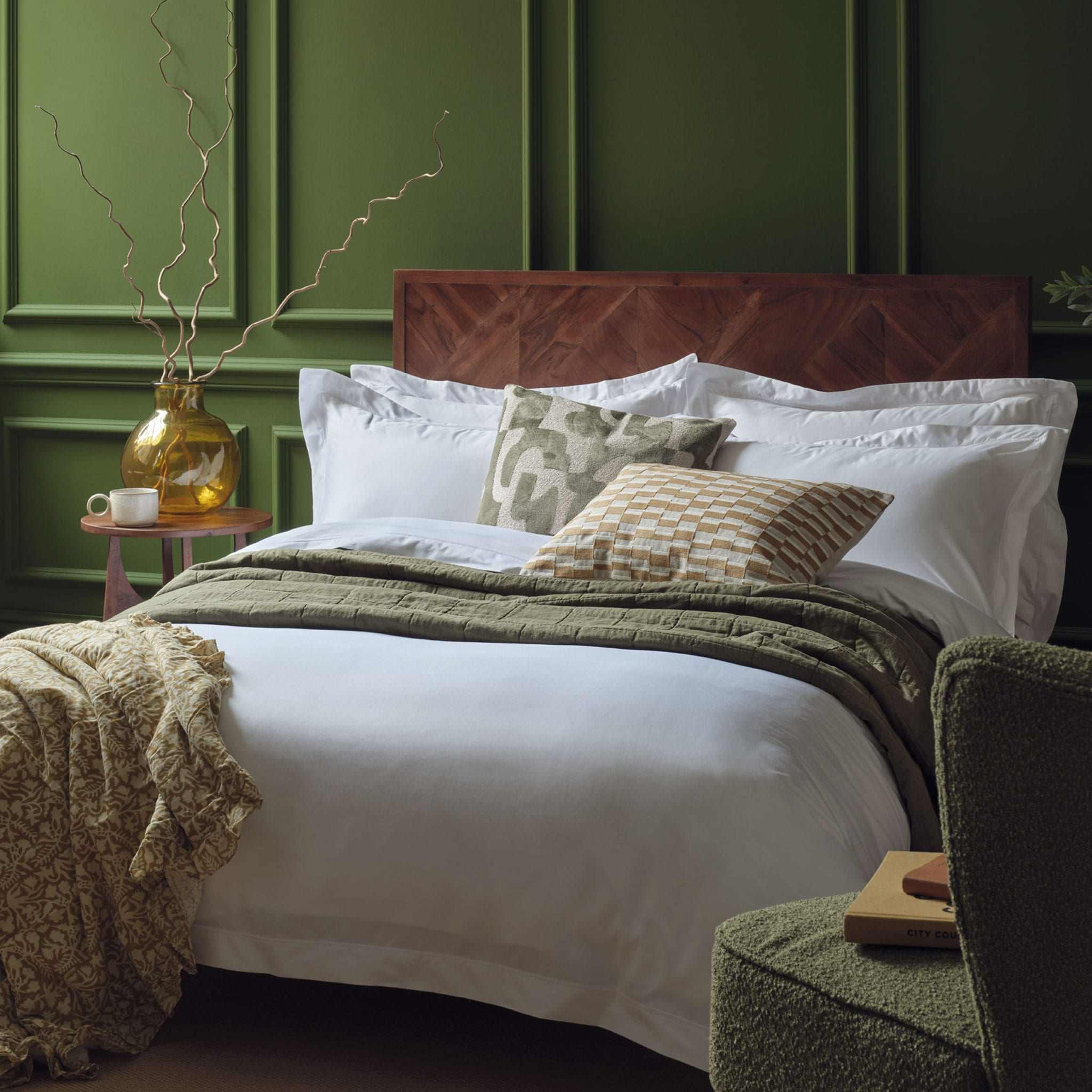 Egyptian cotton bedding in white on a made bed in a luxurious bedroom. Scooms