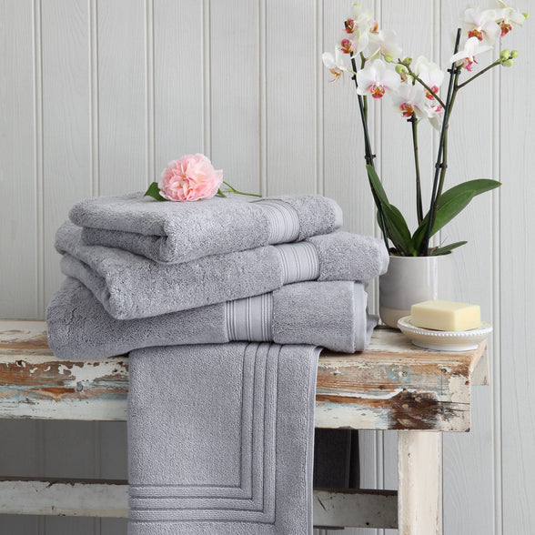 Silver grey Egyptian cotton towels and bath mat on a wooden bench. Scooms