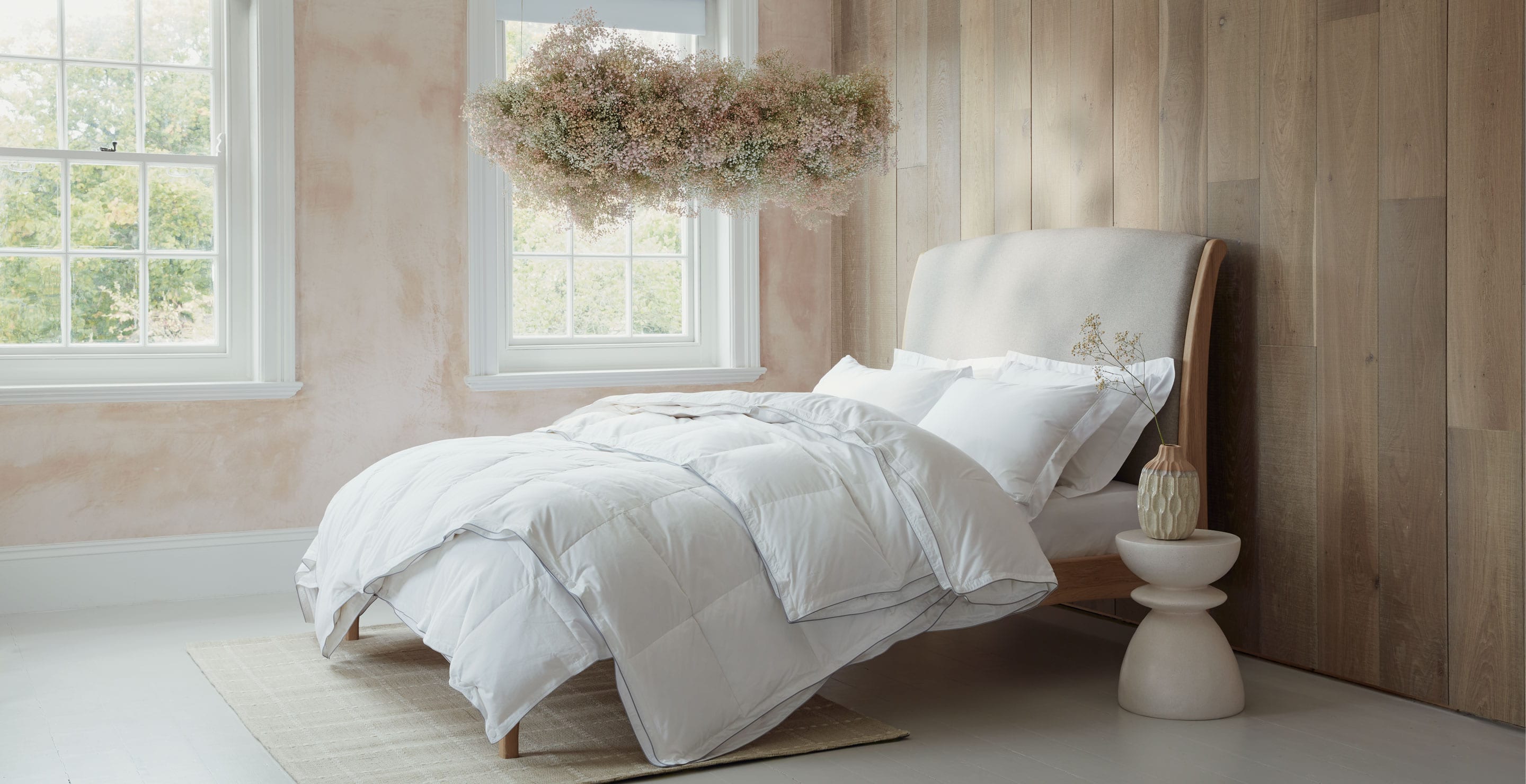 Luxurious Hungarian goose down duvets and pillows on a bed in a modern bedroom. With a flower cloud hanging from the ceiling. Scooms