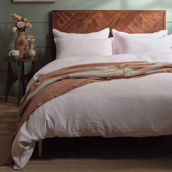 Pink linen bedding on a bed with accessories. Scooms