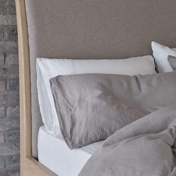Grey and white linen pillowcases on a bed. | Scooms