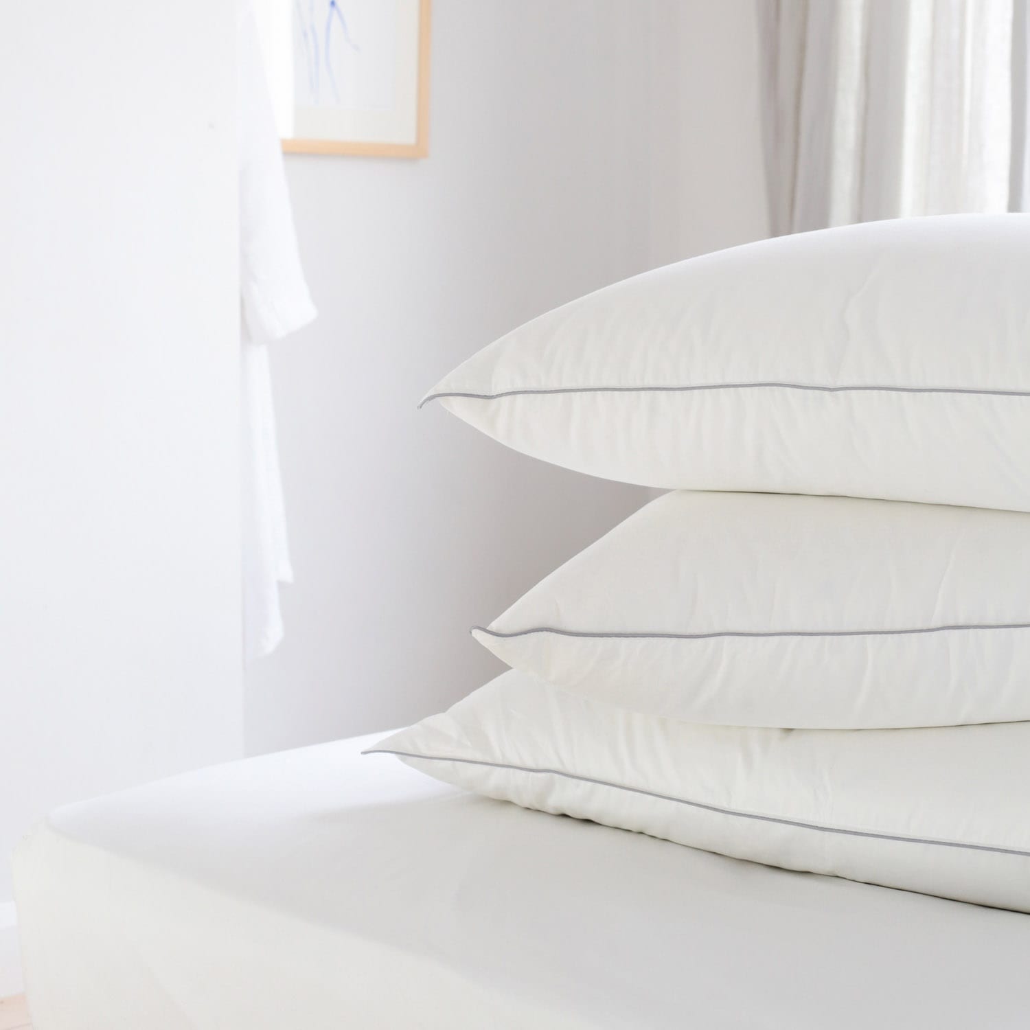 Pile of 3 Hungarian goose down pillows in a white bedroom