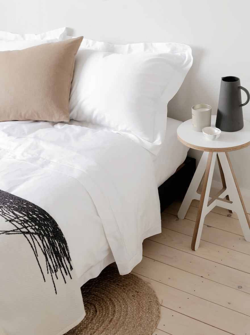 White Sheets on a Bed with a Side Table In a bedroom | scooms