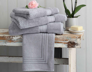 Grey cotton towels on a wooden bench with accessories