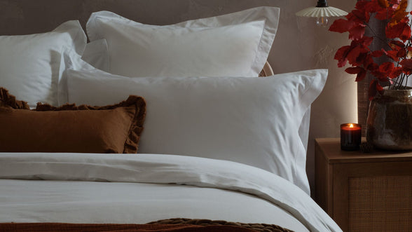 Cosy bed with white sheets, rust throws and a candle
