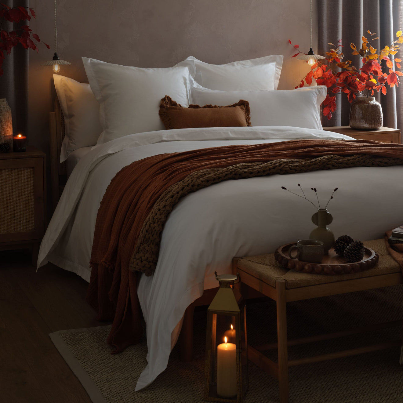 Cosy bedroom, white bedding with rust throw, dim light and candles