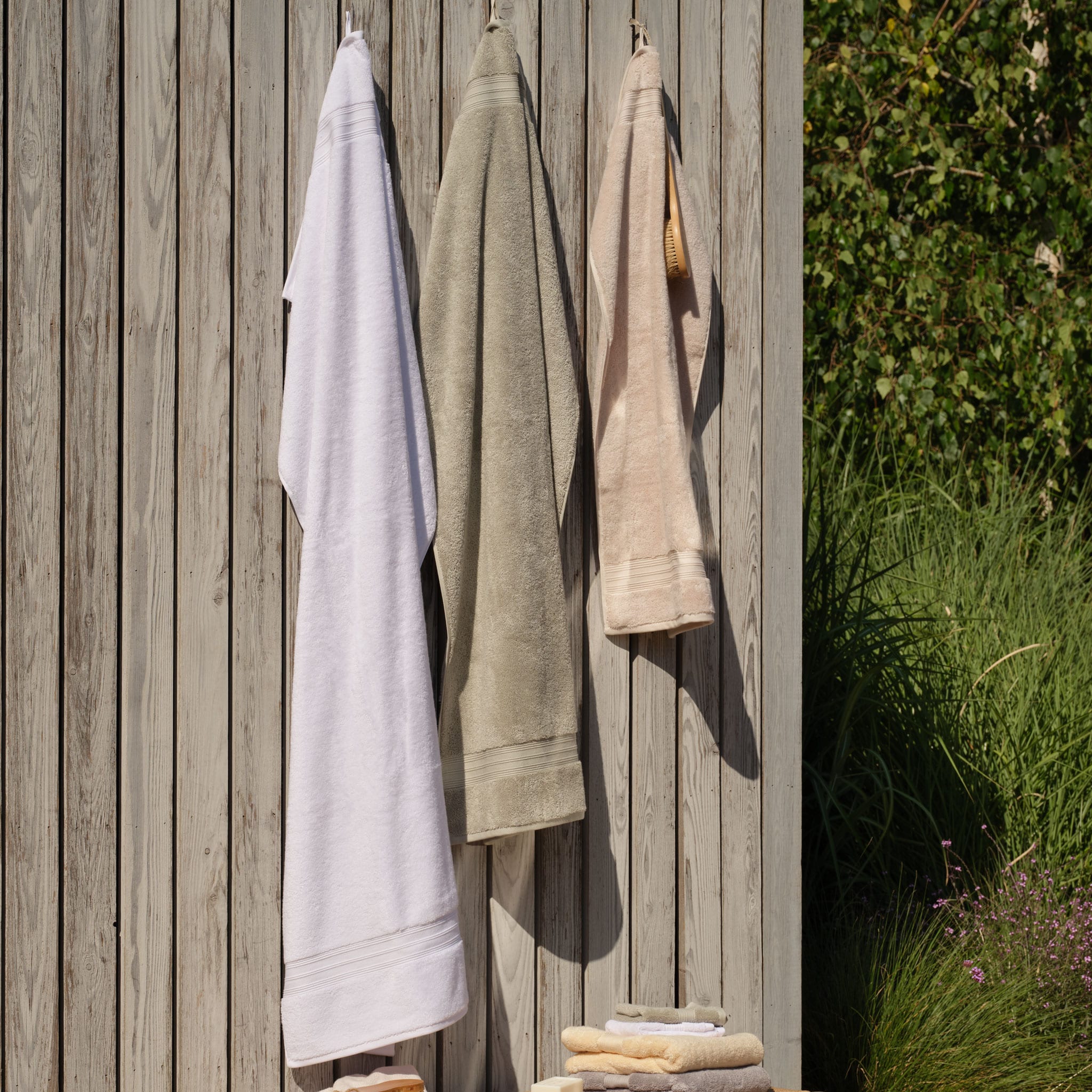 Hanging towels in different sizes, bath sheet, bath towel and hand towel in white green and natural shades. | Scooms