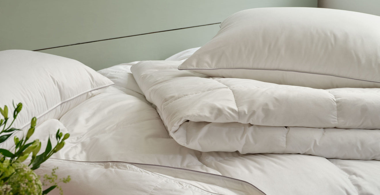 Pillows and duvets lying piled on a bed | Scooms