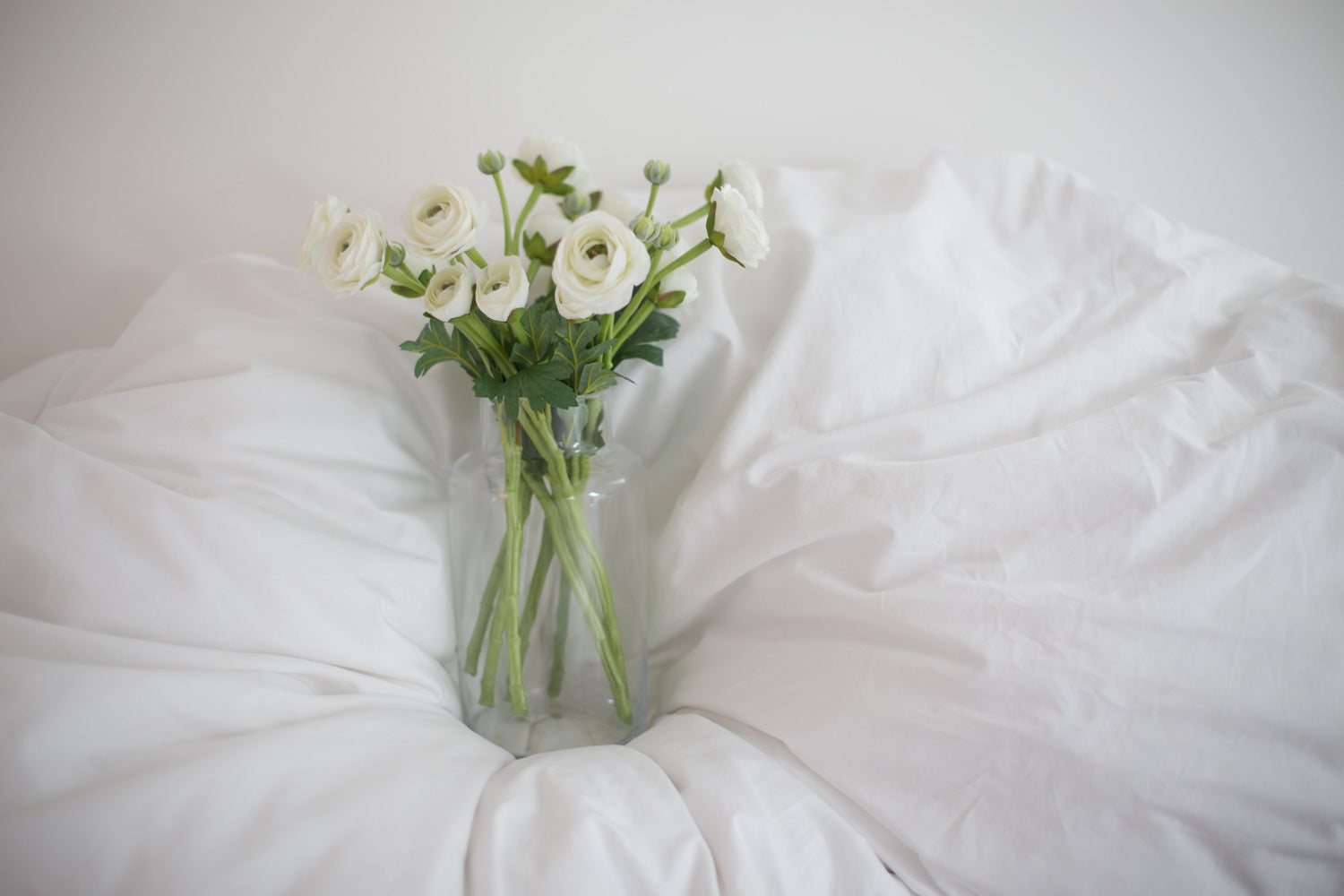 White Flowers in a Vase on Bed Sheets | scooms