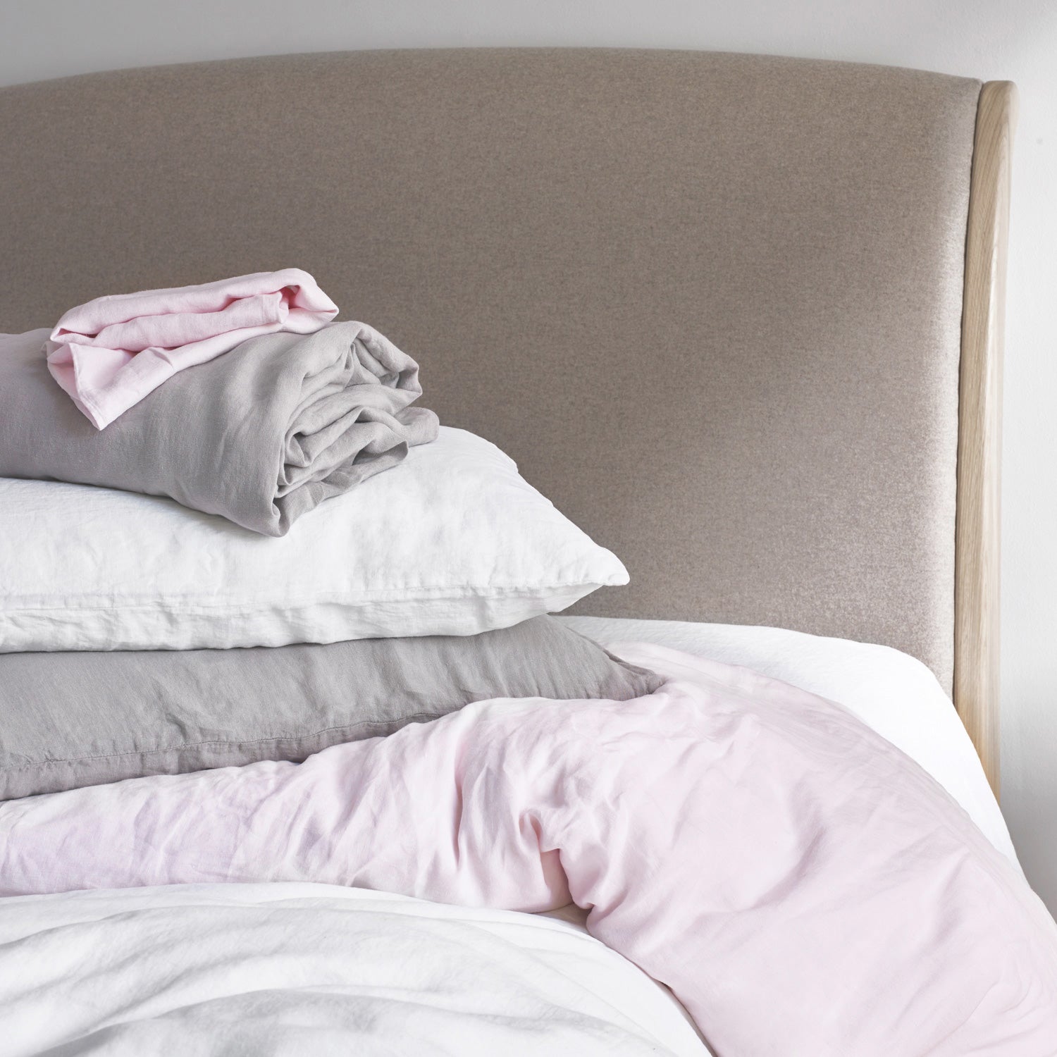 Pile of Freshly Cleaned Linen Bed Sheets and Pillowcases in White, Pink and Grey | scooms