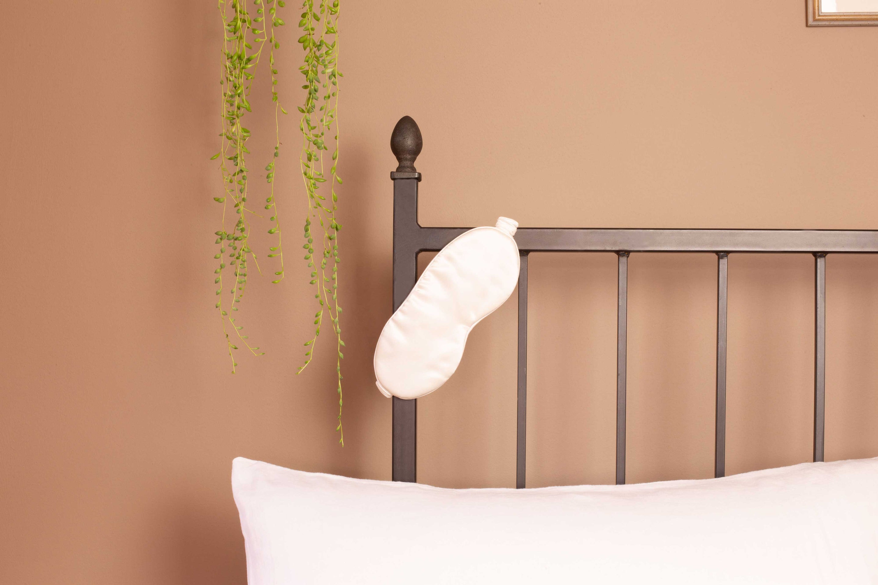 Bed with silk eye mask hanging on headboard | Scooms