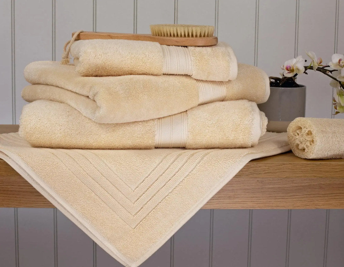 Egyptian Cotton Creme Bath Towels On Wooden Bench With Scrubbing Brush