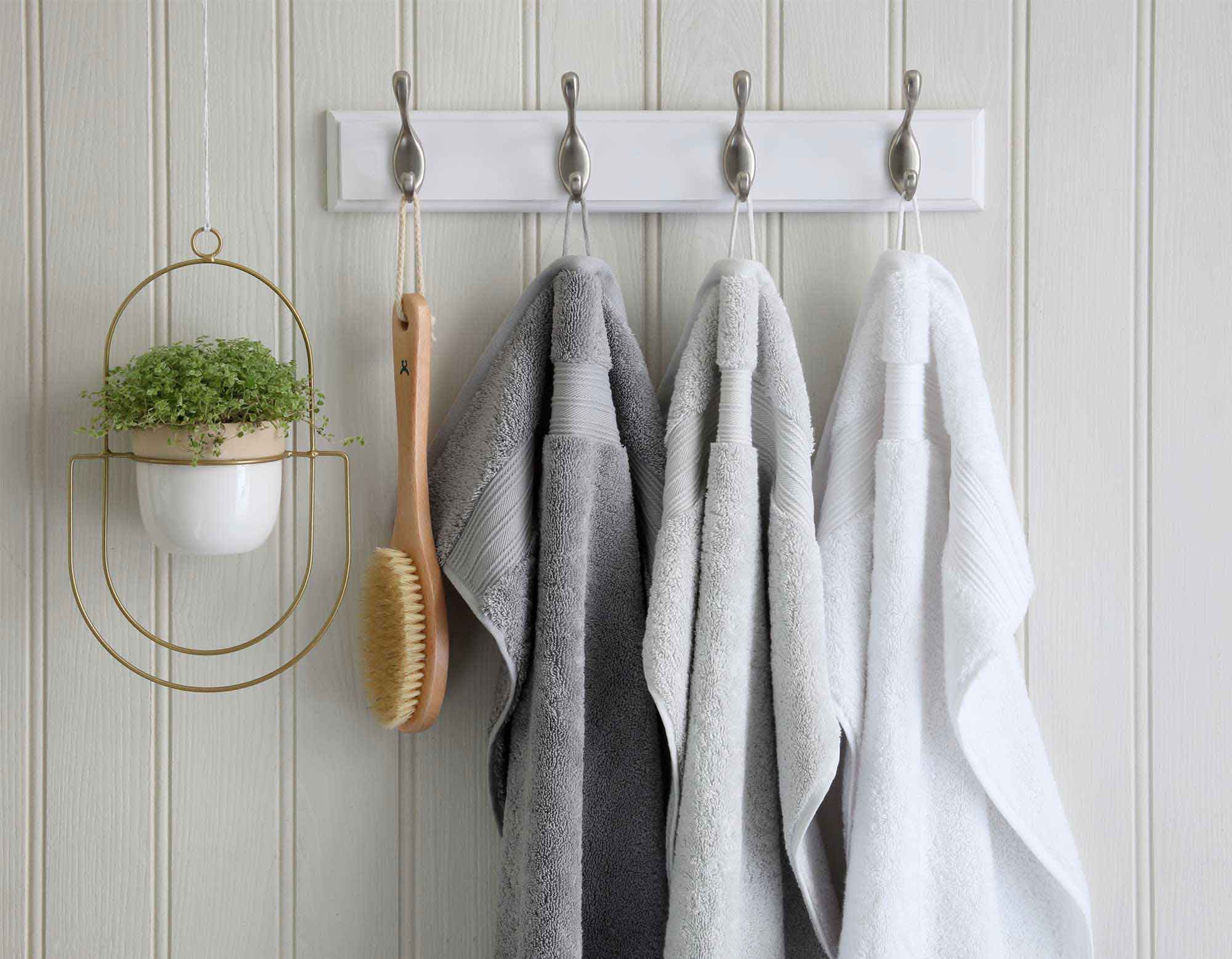 Egyptian cotton bath towels with scrubbing brush hanging from wall hooks