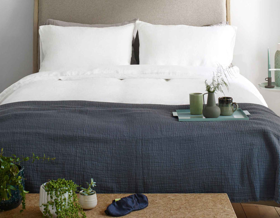 Double white linen duvet cover on made bed in scandi bedroom