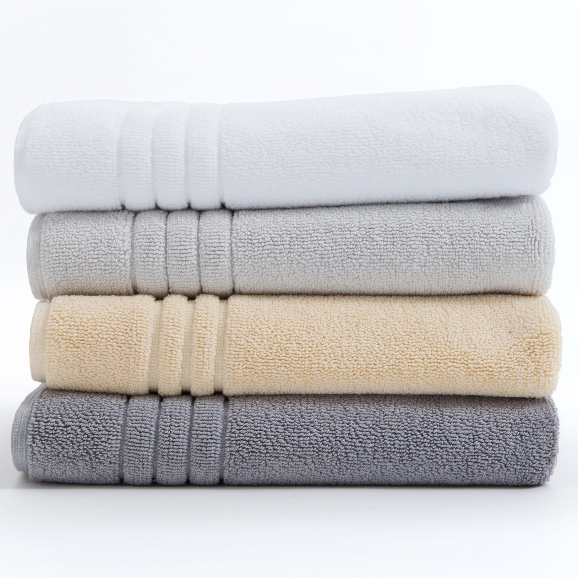White, silver grey, pearl grey, and creme Egyptian cotton bath mats in a pile. Scooms