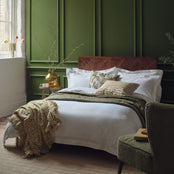 Egyptian cotton bedding in white on a made bed in a luxurious bedroom. Scooms