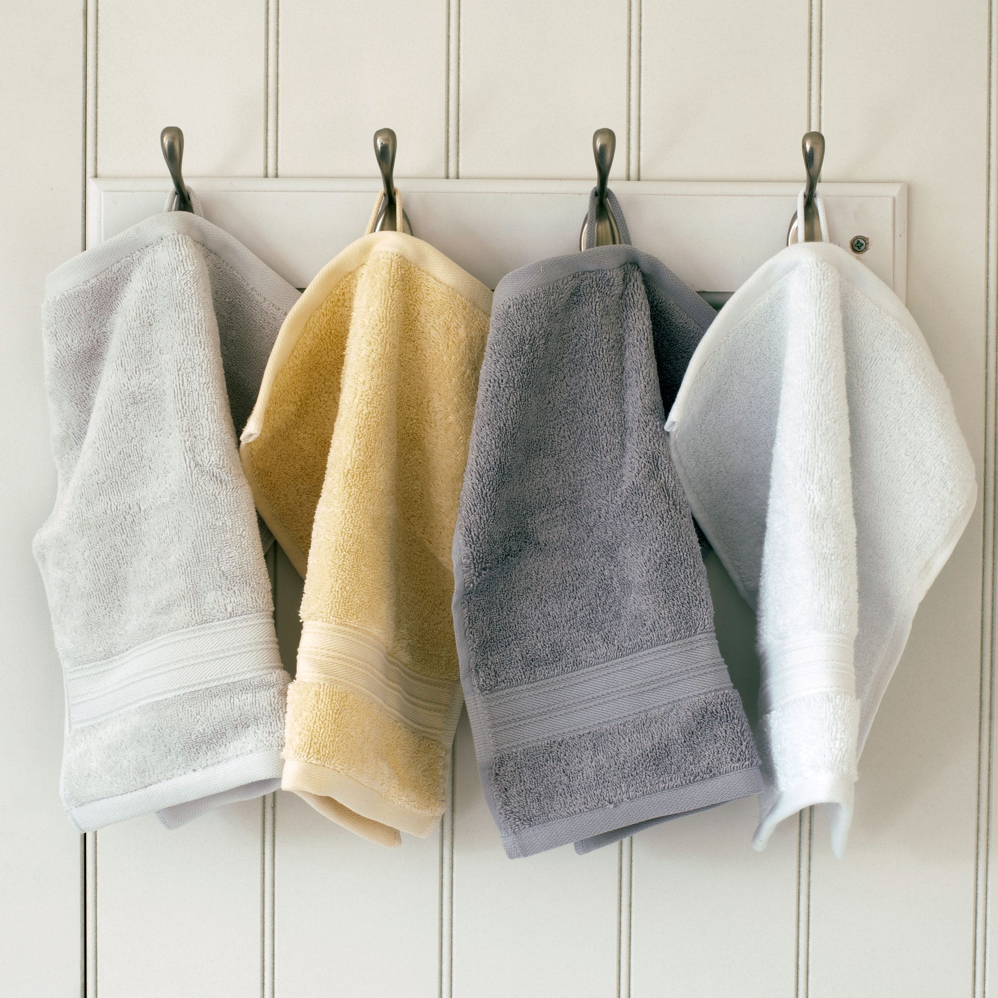 Pearl grey, creme, silver grey and white Egyptian cotton face cloths hanging from hooks. Scooms