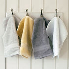 Egyptian cotton hand towel in grey, creme and white hanging from hooks on the wall. Scooms
