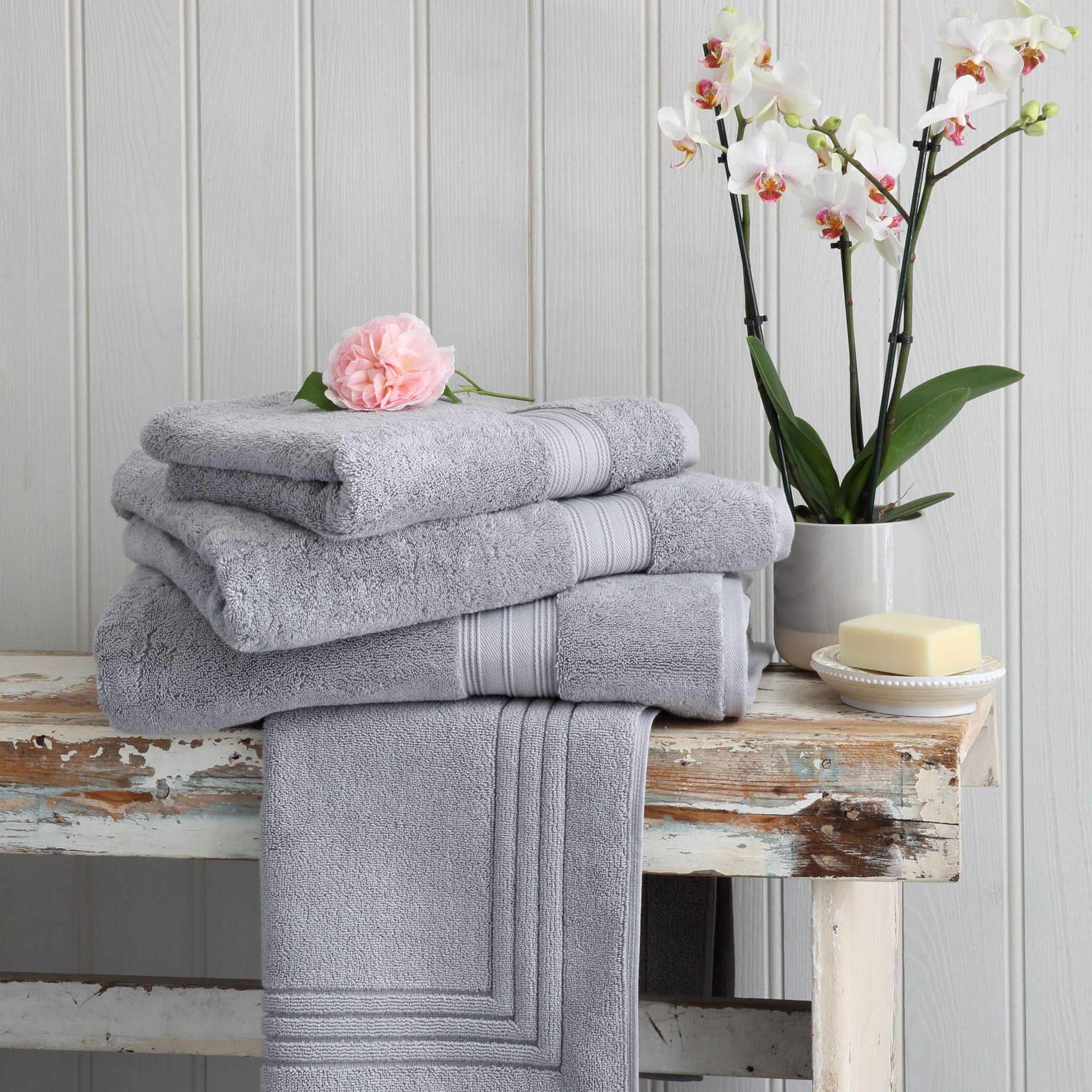 Silver grey Egyptian cotton towels and bath mat on a wooden bench. Scooms