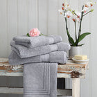 Bundle of grey Egyptian cotton towels, bath mat and face cloth on a wooden bench. Scooms