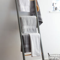 Grey and white Egyptian cotton towels handing from a ladder. Scooms