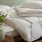 Goose down duvet on a bed, pulled back to show a white cotton mattress protector. Scooms