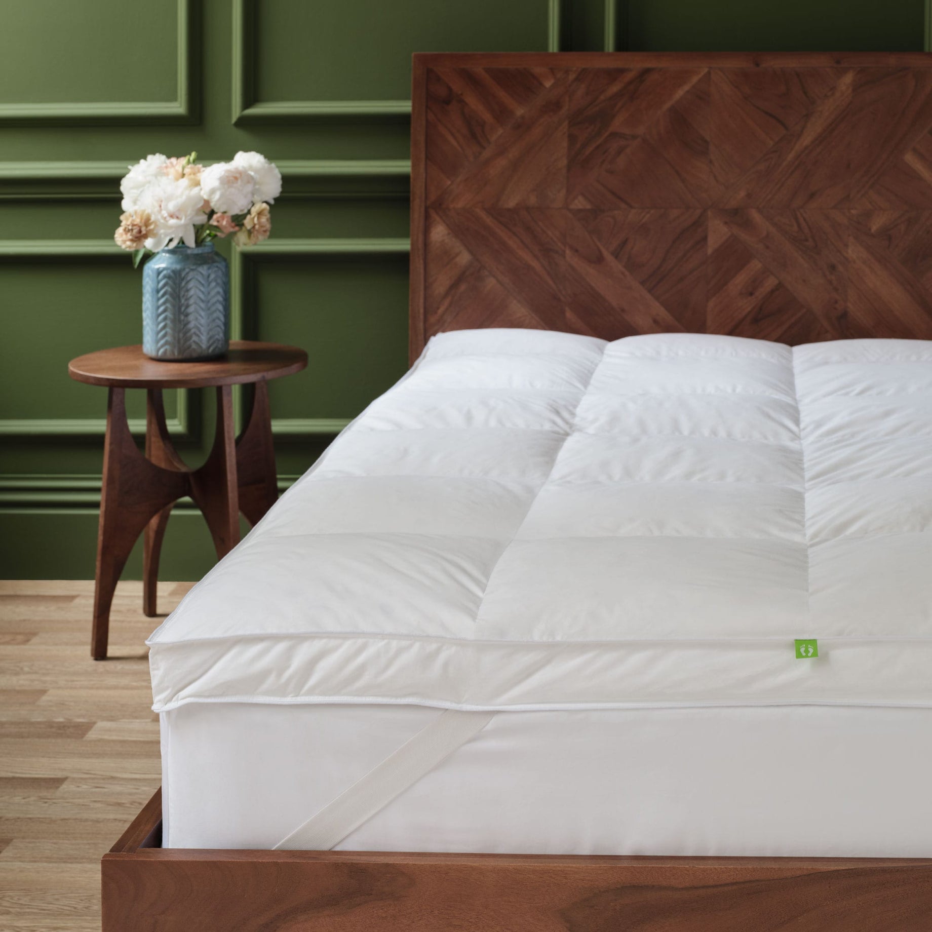 Hungarian feather and down mattress topper on a bed showing the strap to attach it to the mattress,. Scooms