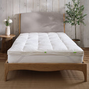 Hungarian feather and down mattress topper on a bed showing the straps to attach it to the mattress,. Scooms