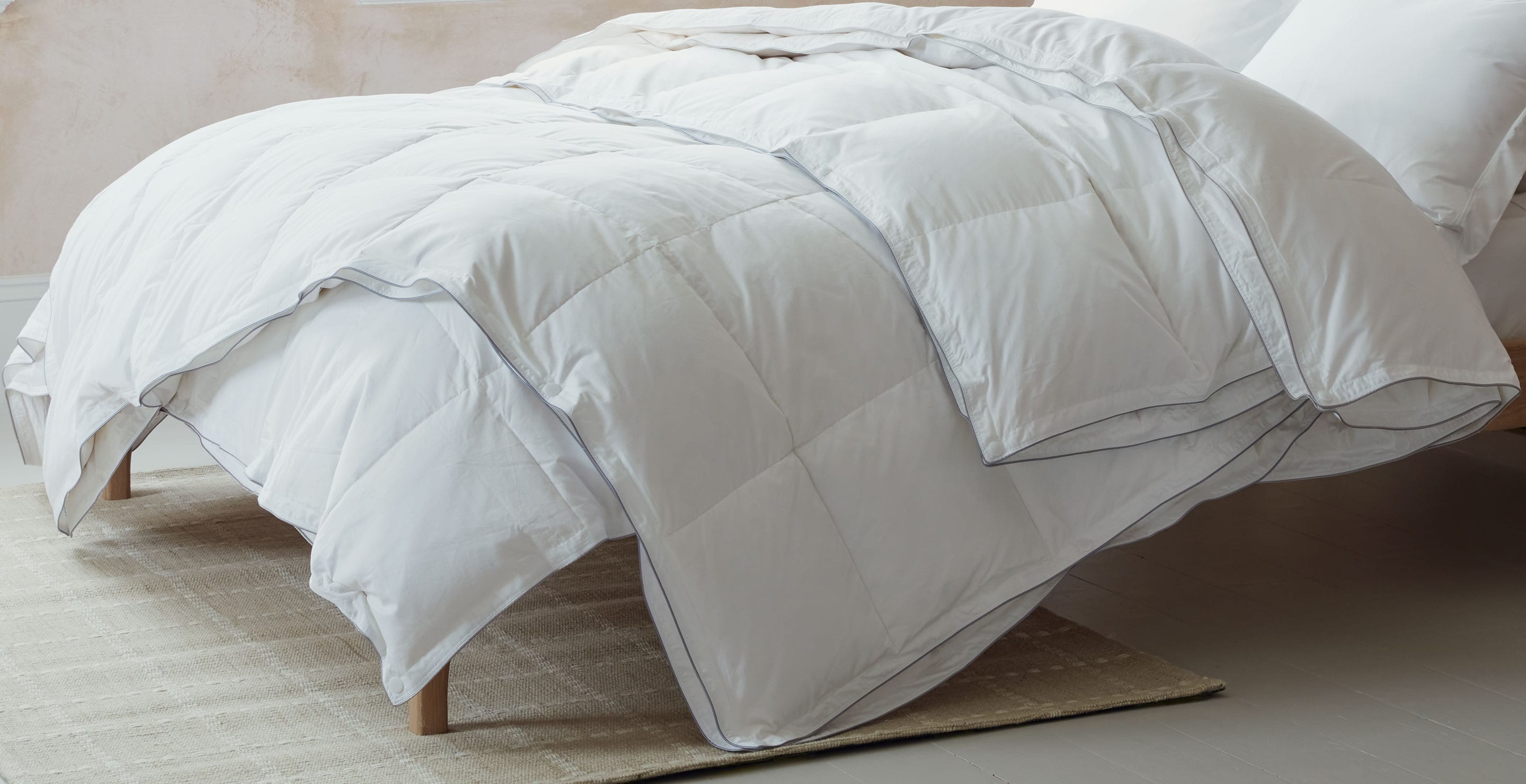 All seasons 13.5 tog duvet, which is made up of a 4.5 tog duvet and a 9 tog duvet draped on a bed. Scooms