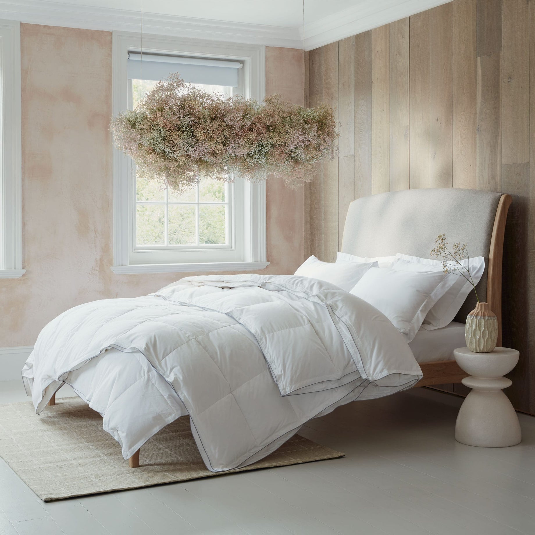 Luxurious Hungarian goose down duvets and pillows on a bed in a modern bedroom. With a flower cloud hanging from the ceiling. Scooms