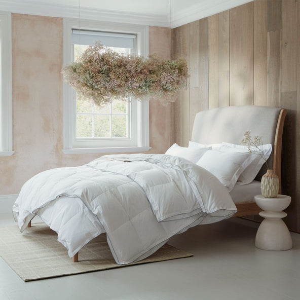 Luxurious Hungarian goose down duvets and pillows on a bed in a modern bedroom. With a flower cloud hanging from the ceiling. Scooms