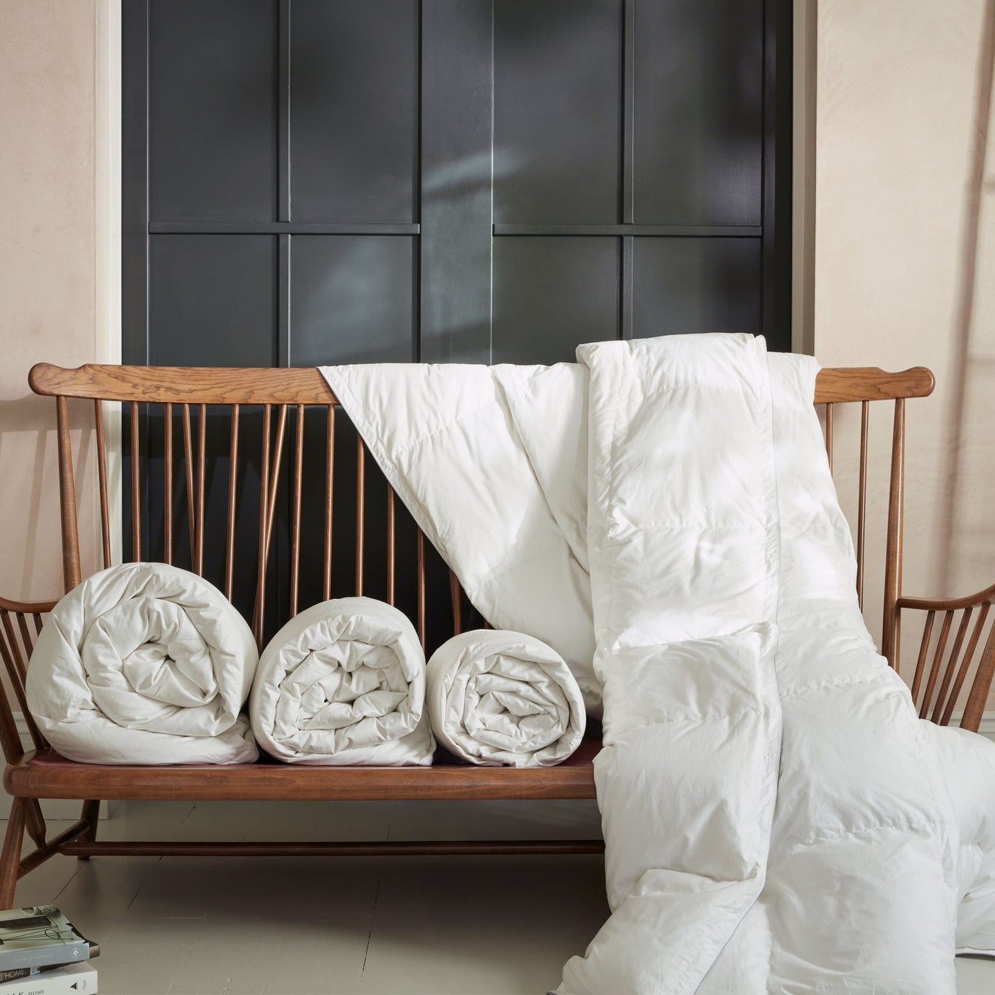 Rolled and draped Hungarian goose down duvets on a wooden bench seat. Scooms