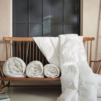 Different size Hungarian goose down duvets on a wooden bench. | Scooms