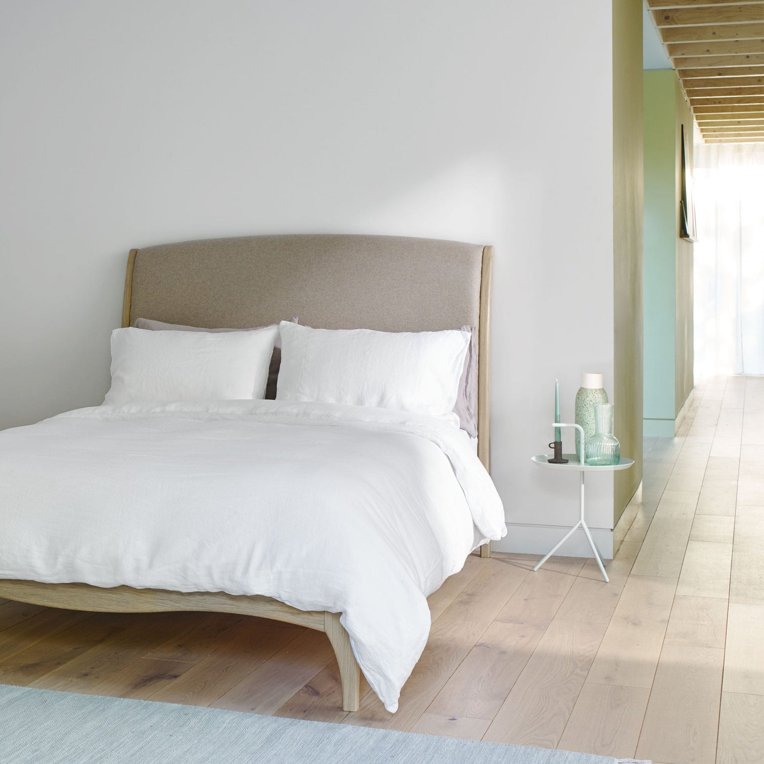 Bed make with white linen bedding in a stark modern bedroom. Scooms