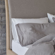 Grey and white linen pillowcases on a bed. Scooms