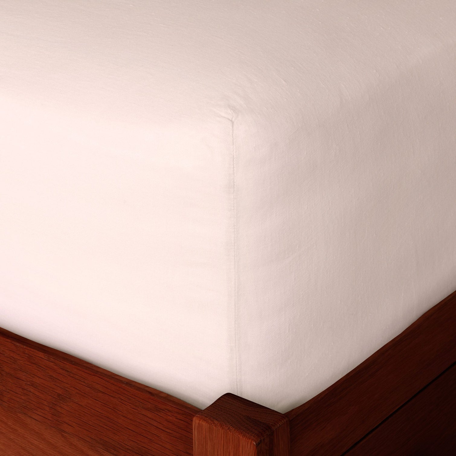 Pink linen fitted sheet on a mattress, corner detail. Scooms