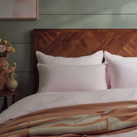 Pink linen bedding on a made bed with accessories. Scooms