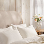 Light and airy bedroom with bed made with white linen bedding. Scooms