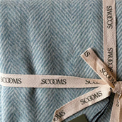 Close-up of a herringbone-patterned blue coloured Merino lambswool throw with 'Scooms' branding.