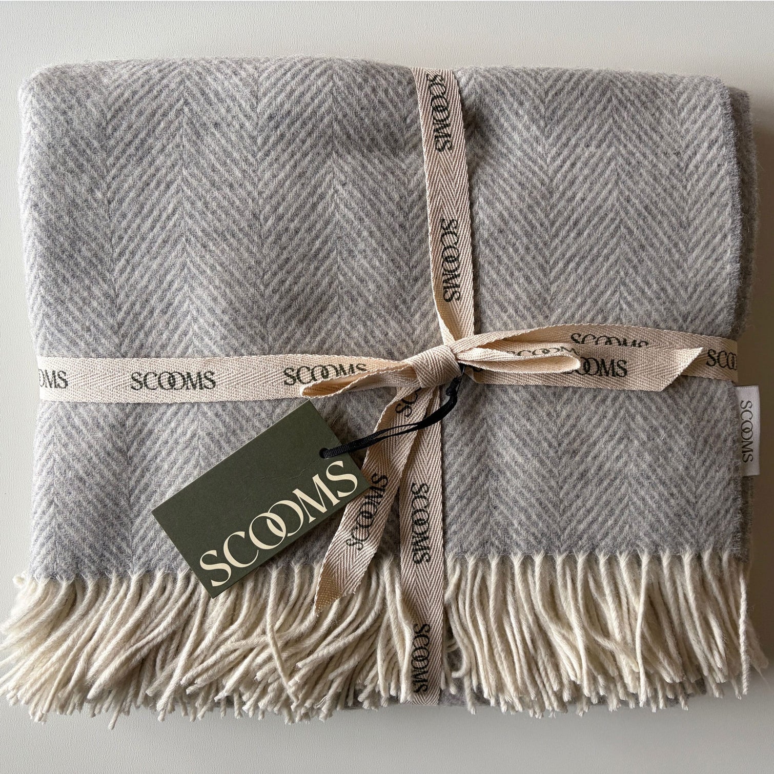Herringbone-patterned grey coloured Merino lambswool throw with 'Scooms' branding.