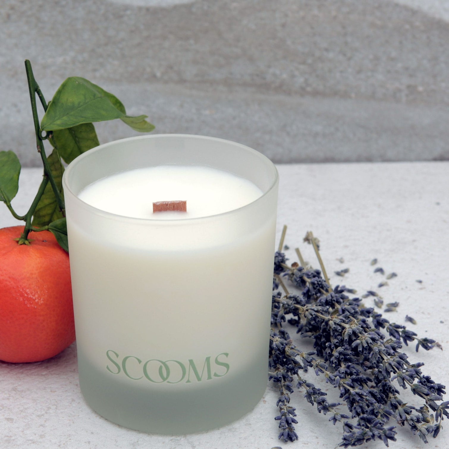 Natural scented candle in a frosted glass jar with an orange, lavender and leaves | Scooms