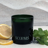 Natural scented candle in an emerald green glass jar next to a lemon, mint and lavender | Scooms