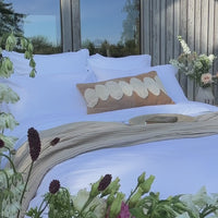 White percale Egyptian cotton bed linens on a bed outside, styled with a Scooms natural throw | Scooms