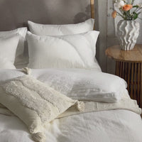 White linen bedding in a made bed. Scooms