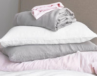 Pile of linen bedding in grey, pink and white