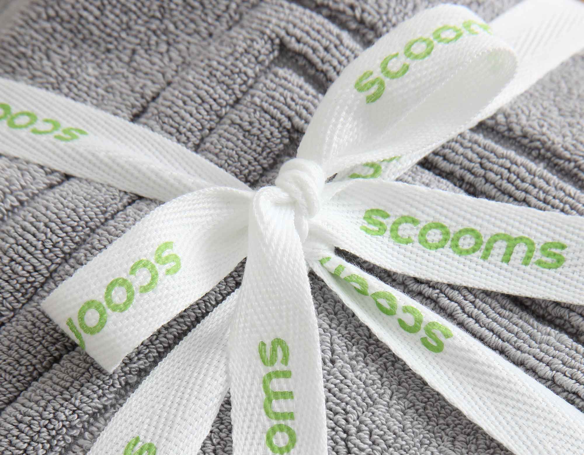 Close up of silver grey cotton bath mat folded and tied with scooms ribbon