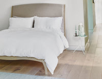 Superking white linen duvet cover on made bed in Scandi style bedroom with wood floor