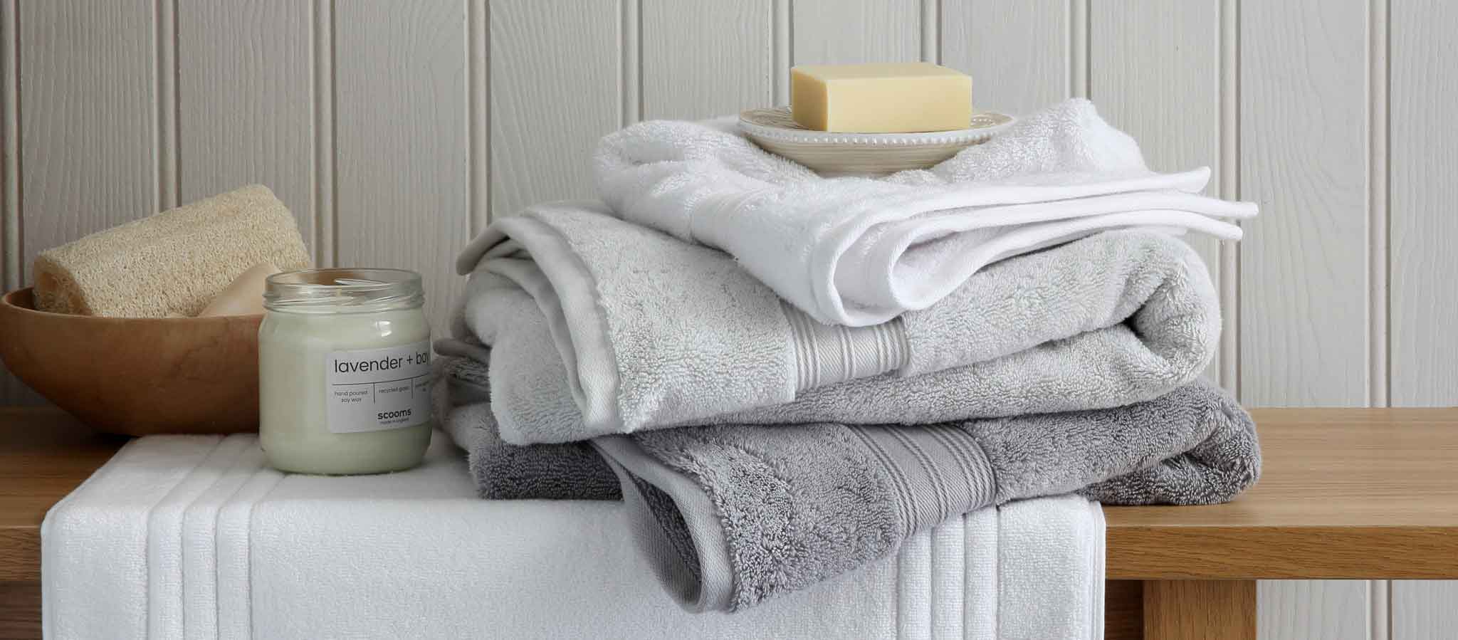 Egyptian cotton towels piled on bench with candle and loofah