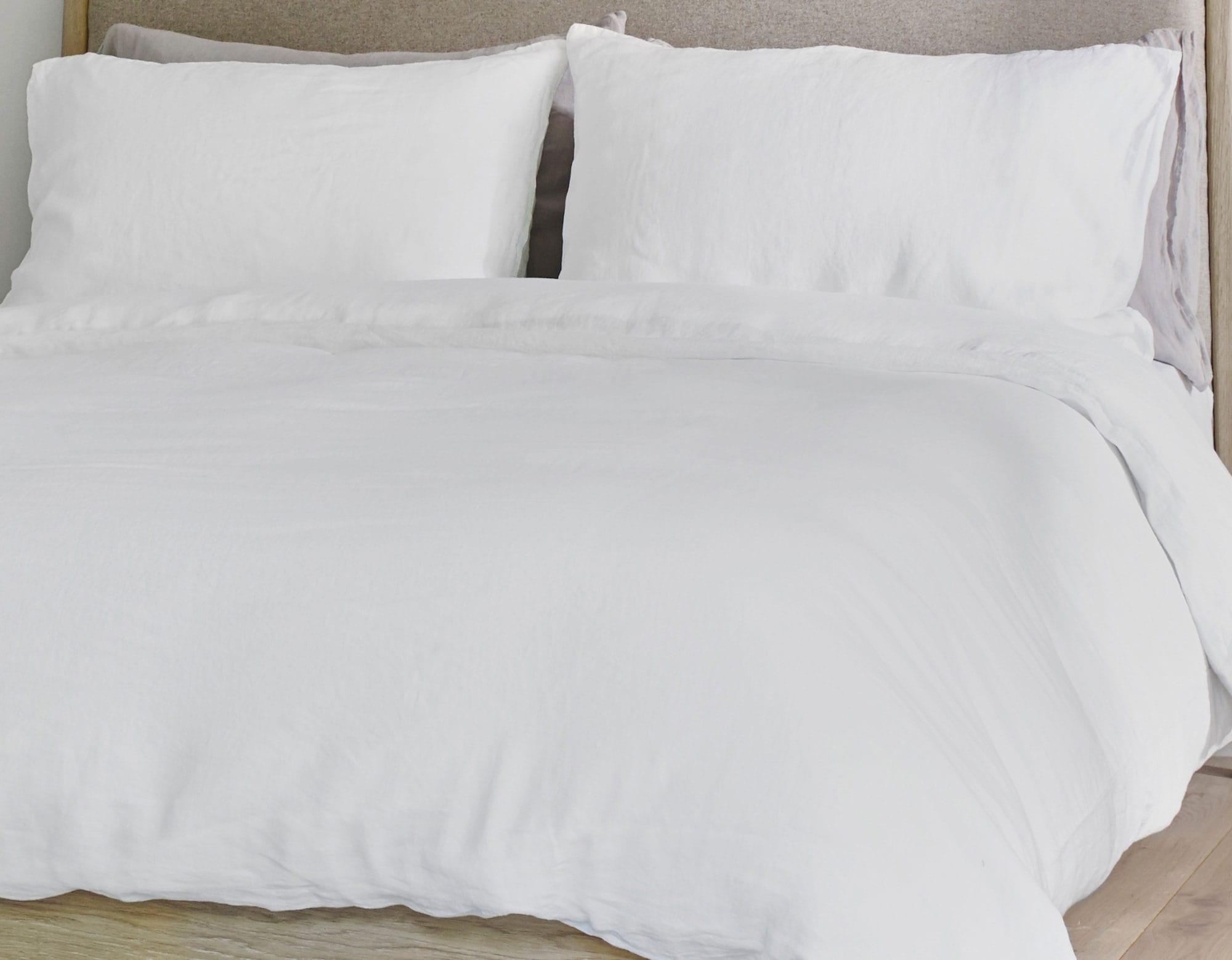 White linen bedding on bed showing duvet cover, pillowcases and fitted sheet